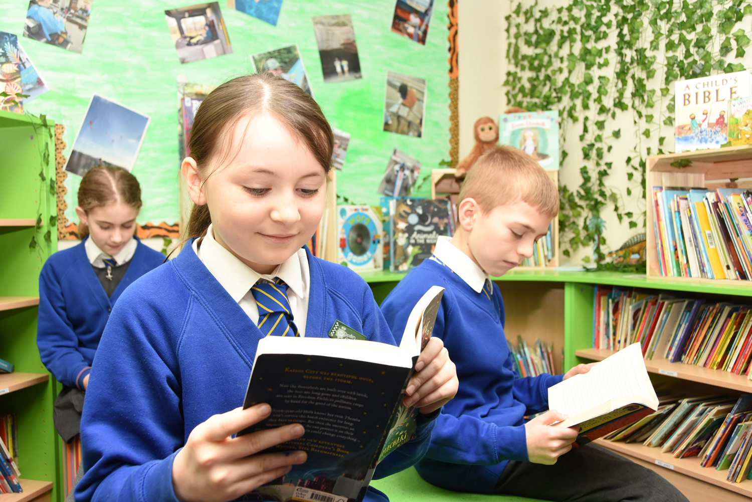 Three Parkside pupils reading books in the library area.